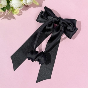 Détail d'une élégante pince à cheveux en satin noir avec nœud et longs rubans
