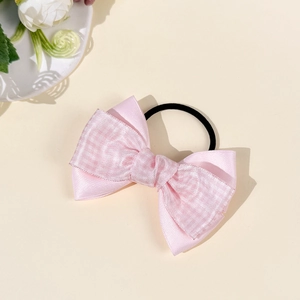 Detail of pink satin bow hair tie with layered design and black elastic rubber band