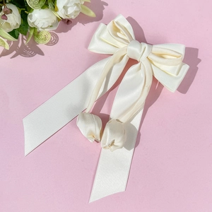Pince à cheveux élégante en satin blanc avec longs rubans et pendentif tulipe sur fond rose