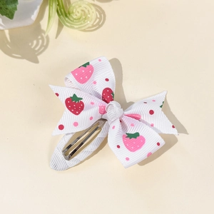 Detailed view of handmade bow hair clip with pink strawberry and polka dot print pattern