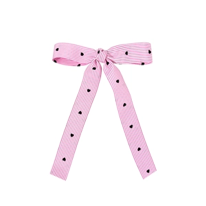 Pink and white striped bow hair clip with black heart patterns and long ribbon streamers