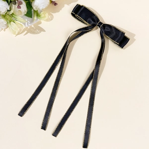Dettaglio del fiocco per capelli in raso nero con bordi dorati e lunghi nastri eleganti