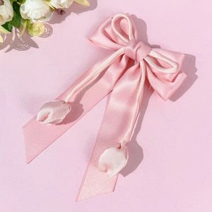 Détail d'une pince à cheveux à nœud rose en satin avec élégants pendentifs tulipes