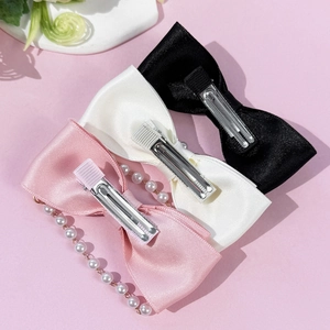 Lot de trois barrettes nœuds rose, blanc et noir avec frange de perles sur fond rose