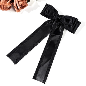 Détail d'une pince à cheveux en satin noir élégante avec bords volantés et longs rubans