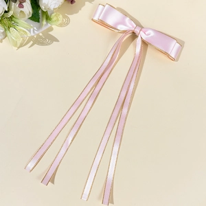 Fiocco per capelli in raso rosa con bordo dorato e lunghi nastri fluenti in dettaglio