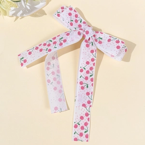 Détail d'une pince à cheveux nœud avec motif cerises roses et longs rubans