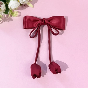 Détail de la barrette à nœud en satin bordeaux avec breloques tulipes et rubans