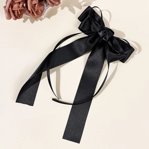 Détail d'une barrette nœud en satin noir élégante avec ornement rose et longs rubans