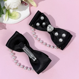 Vue détaillée des barrettes nœuds en satin noir avec strass cœur et franges perles