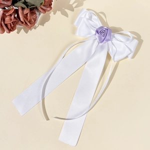 Détail d'un nœud en satin blanc avec une rose lavande délicate et de longs rubans fluides