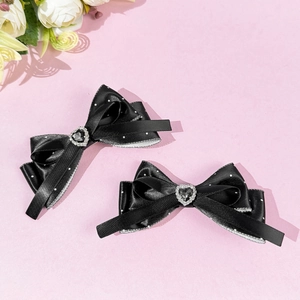Detail of black bow hair clips with white polka dots and heart-shaped rhinestones