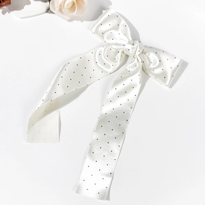 Detailed view of white polka dot satin bow hair clip with elegant long ribbons on white