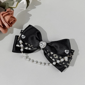 Détail d'une pince à cheveux nœud léopard avec strass cœur et chaîne perles