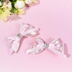 Detailed view of pink polka dot bow hair clips with silver heart rhinestone centers