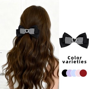 Detail of plaid bow hair clip with heart rhinestone on brown wavy hair for women