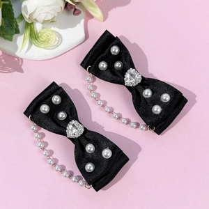 Détail de barrettes Lolita avec nœuds en satin noir, strass en cœur et glands de perles