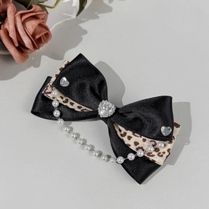 Détail de la pince à cheveux noeud léopard avec strass cœur et chaîne de perles