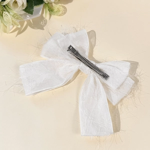 Gros plan d'un nœud papillon blanc en tissu texturé avec pince crocodile en métal