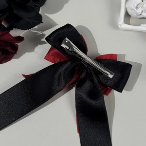 Gothic skull cross hair clip with layered black and red satin ribbon bow and metal grip