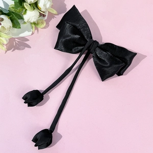 Close-up of black satin bow hair clip with elegant long ribbons and tulip floral charms