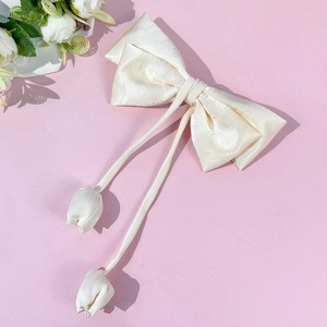 Elegant cream satin bow hair clip with chic tulip pendants on pink background
