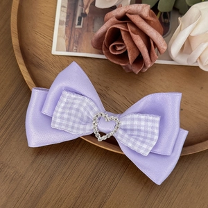 Detailed shot of a purple ribbon bow hair clip with a sparkling rhinestone heart center