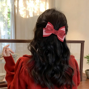 Détail d'un nœud pour cheveux rouge avec bordure pied-de-poule et pendentif rubis