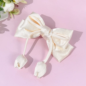 Detail of cream satin bow hair clip featuring elegant hanging tulip fabric pendants