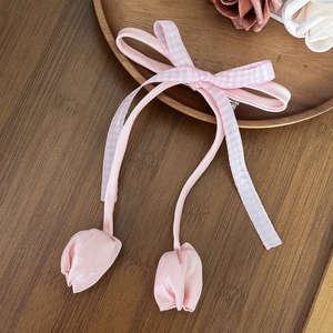 Detalle de la pinza para el pelo con lazo rosa y colgantes de tulipanes en madera