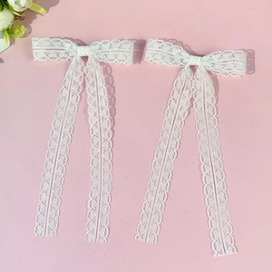 Détail de barrettes en dentelle blanche avec motif cœur et longs rubans élégants
