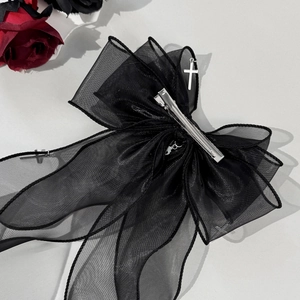 Détail du nœud en organza noir avec pendentif croix argentée de style gothique lolita