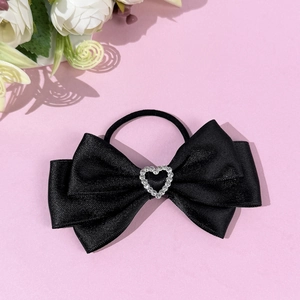 Ballet style black bow hair tie with rhinestone heart on a soft pink background