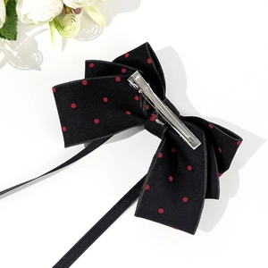 Elegant black bow hair clip with red polka dots and long ribbons on white background