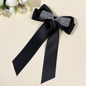 Détail d'un nœud en satin noir avec rubans à carreaux et strass en forme de cœur