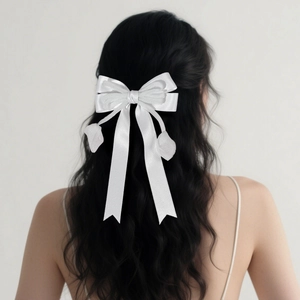 Barrette nœud en satin blanc avec longs rubans portée sur une coiffure mi-haute
