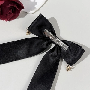 Gothic black satin bow hair clip with gold star charms and red rose decorative accent