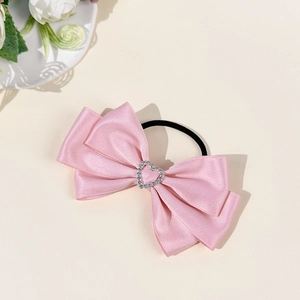 Detailed shot of pink satin bow hair tie with sparkling heart rhinestone centerpiece
