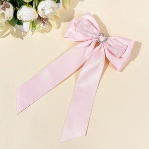 Détail de la pince à cheveux en satin rose avec un cœur scintillant en strass