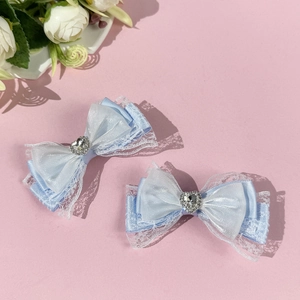 Light blue lace bow hair clips with rhinestone heart detail on a pink background