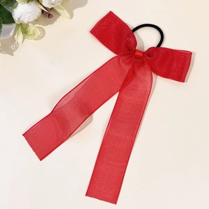 Elegant red mesh bow hair scrunchie with long ribbons and subtle shimmer on beige background