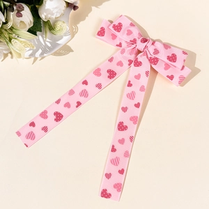 Dettaglio del fermaglio per capelli con fiocco rosa a cuori e nastro a coste