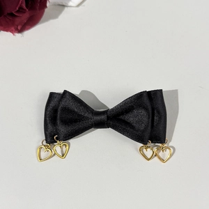 Detail of black satin bow hair clip with gold heart-shaped metal pendants decoration
