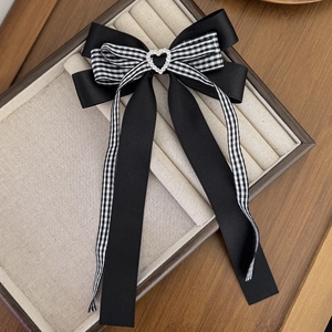 Détail de la barrette à cheveux style britannique avec nœud noir et strass en cœur