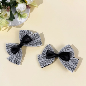 Gros plan de barrettes à nœuds en satin noir et dentelle blanche aux motifs floraux