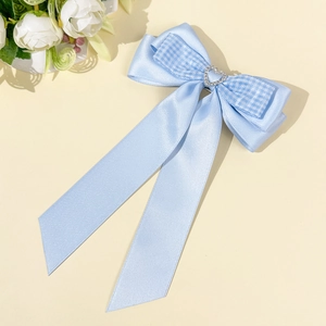 Détail d'une pince à cheveux nœud en satin bleu clair avec tissu à carreaux et strass