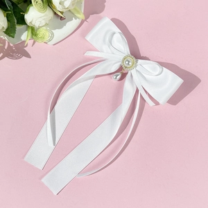 Détail du nœud papillon en satin blanc avec perle et élégant pendentif en goutte