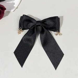 Detail showing a black satin bow hair clip with decorative gold star-shaped pendants
