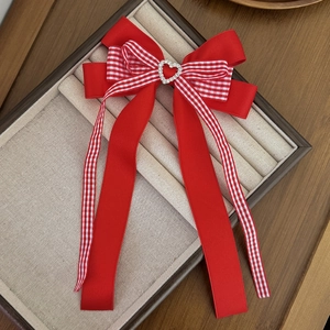 Détail d'un nœud à cheveux rouge à carreaux avec strass en cœur et longs rubans élégants