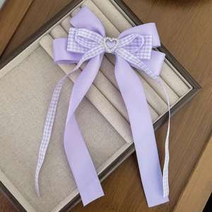 Détail d'un nœud papillon violet avec strass en cœur et longs rubans pour cheveux